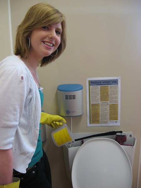 Amanda Bierre measuring how much water is wasted from a leaking toilet.